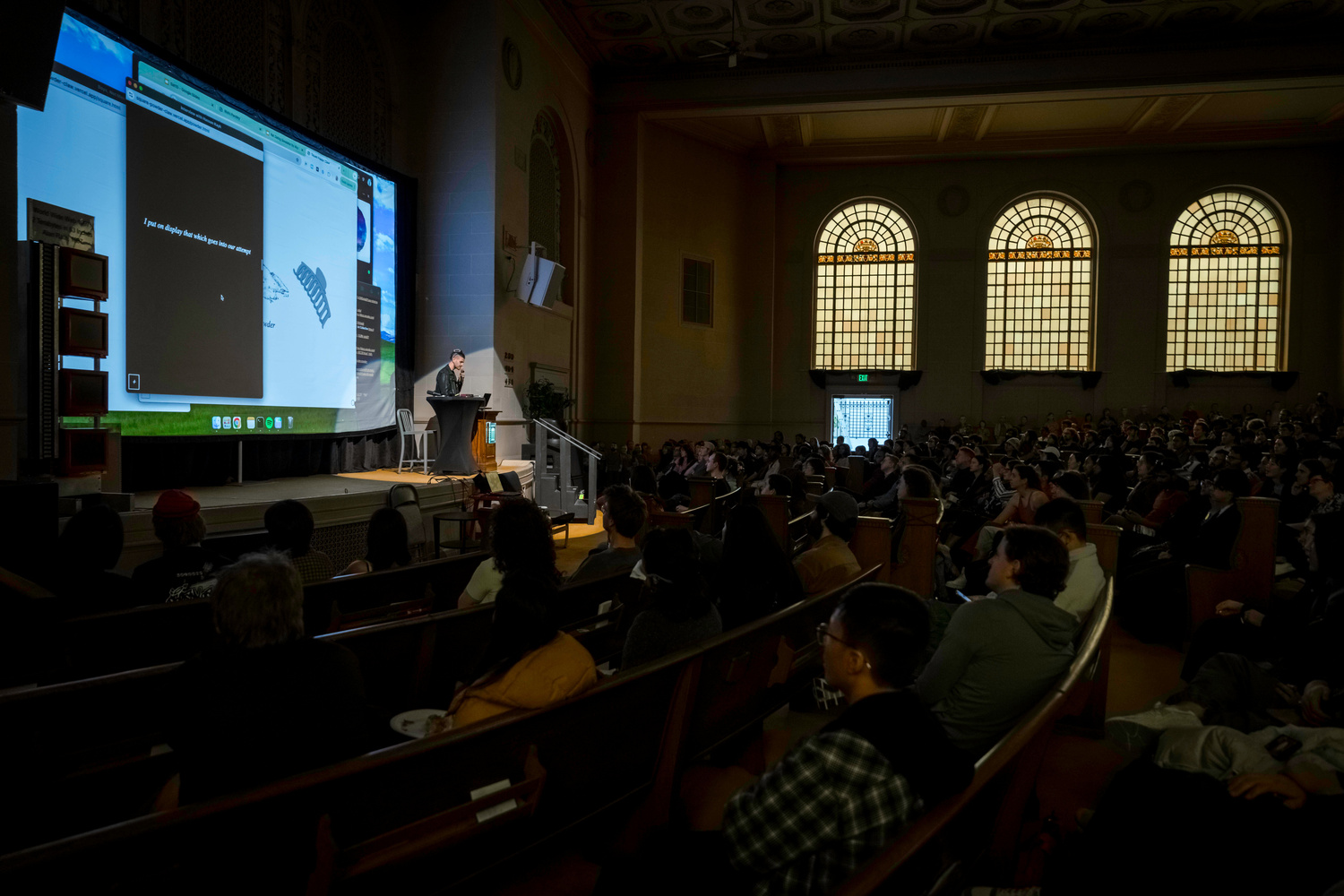 Halim performing computer theater in a grand hall, the machine projected behind him.