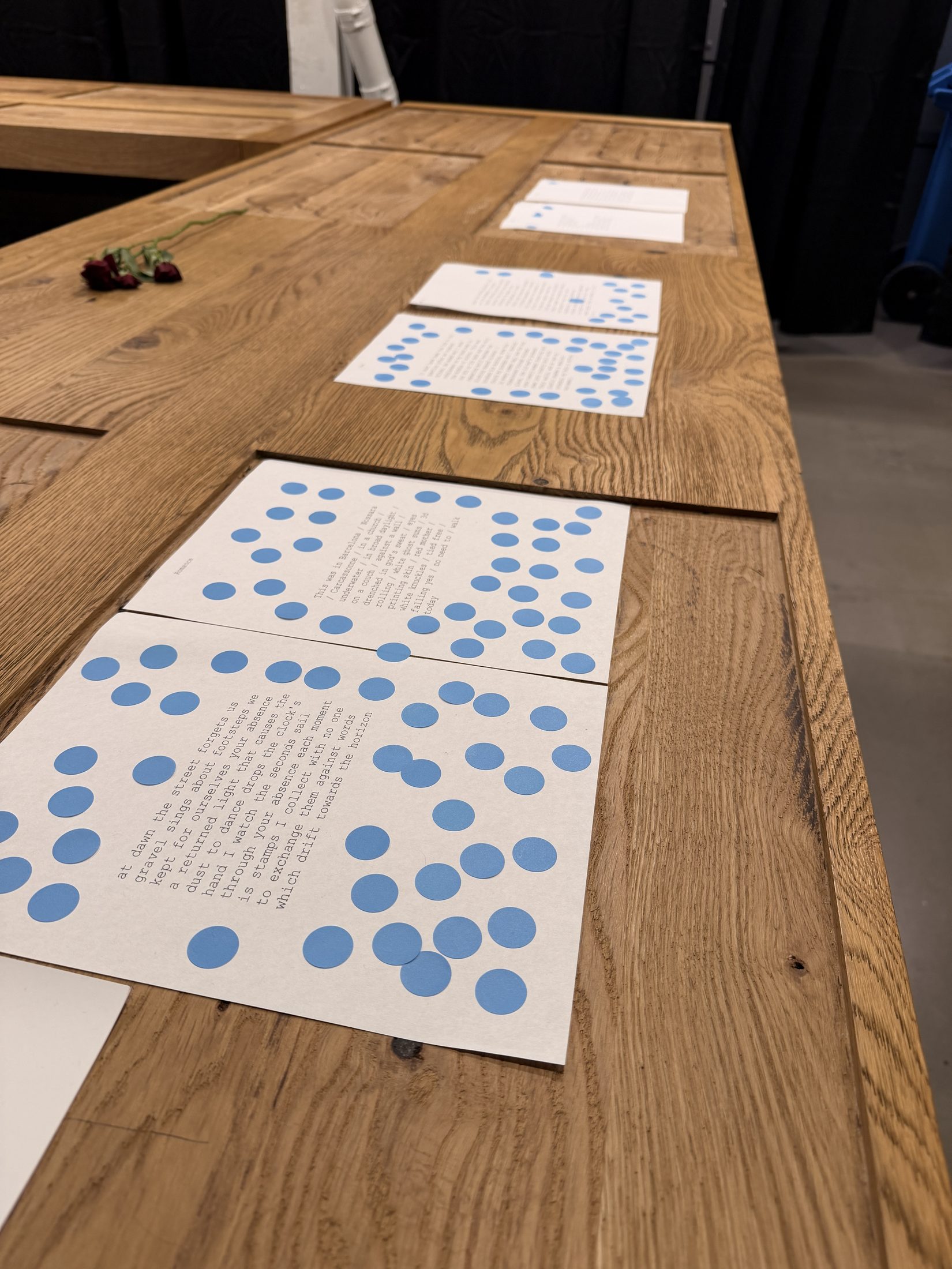 Poems lined up along a wooden ledge with blue stickers accumulating