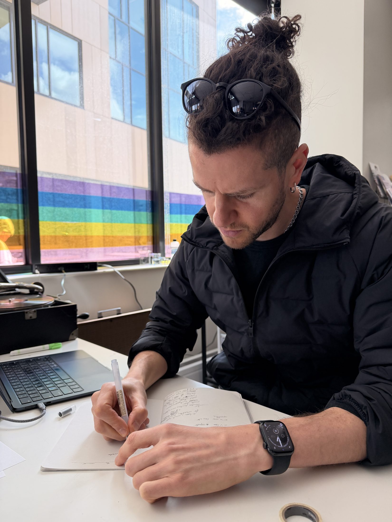 The poet writing with a rainbow flag and lab equipment in the background