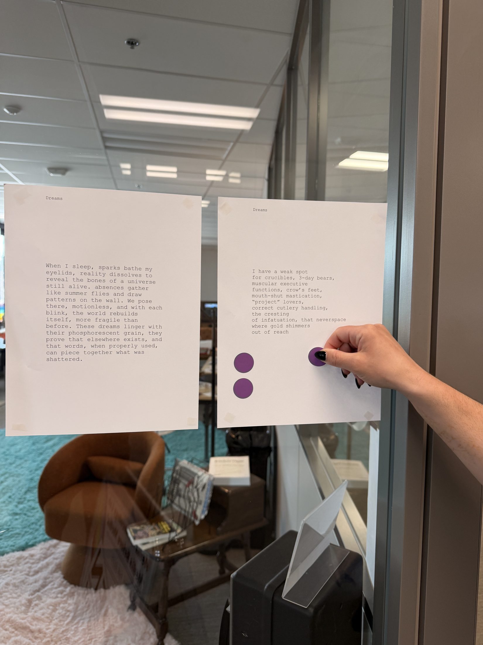 A hand placing a purple voting sticker on printed poems